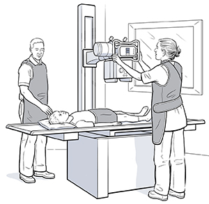 Niño acostado boca arriba sobre una mesa y debajo de un aparato de radiografía. Un proveedor de atención médica está colocando la máquina en posición.